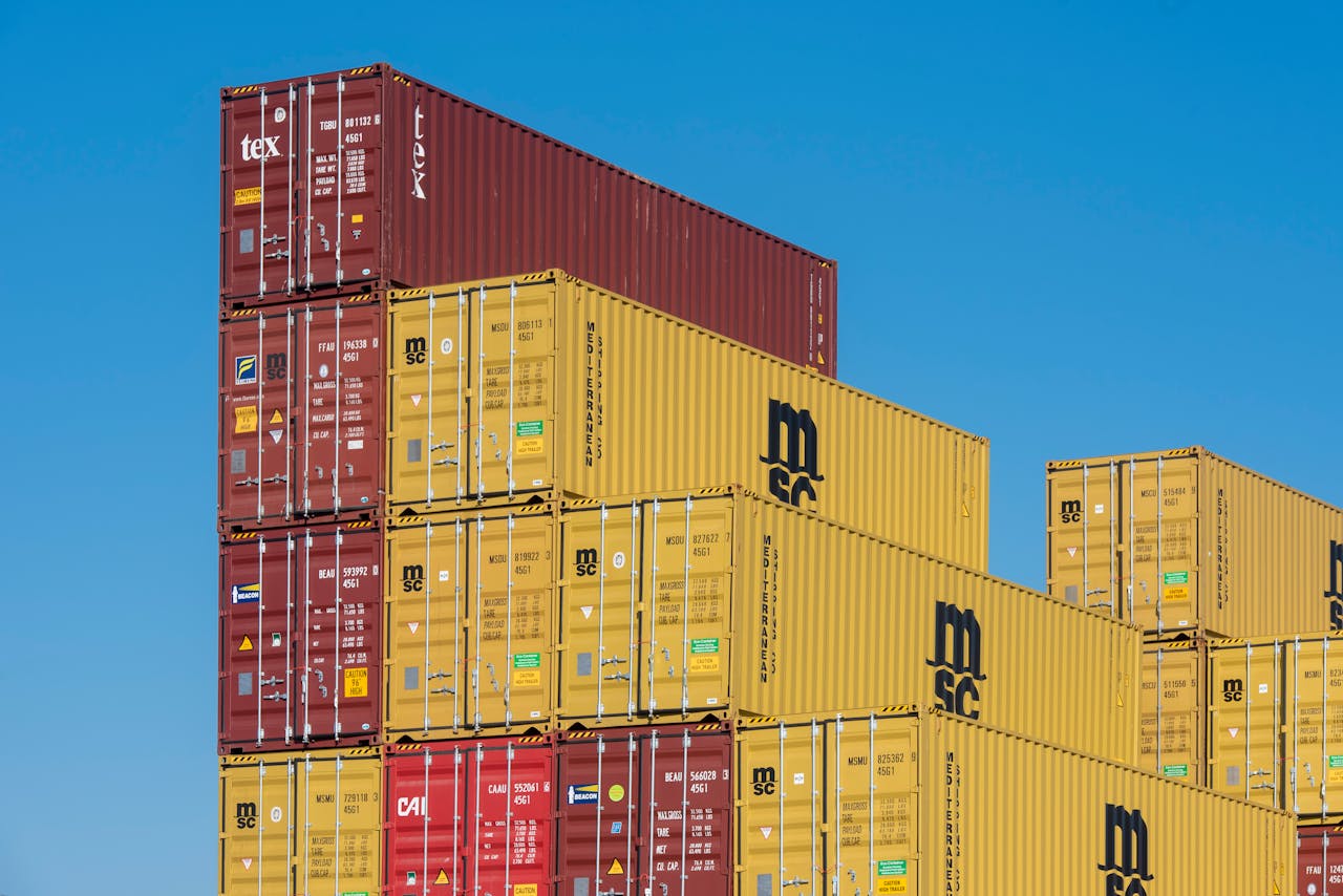 Colorful shipping containers stacked high under a clear blue sky, displaying industrial logistics.